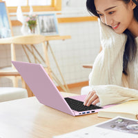 ピンク色ノートパソコンを操作する女性、明るい室内で快適に使用中